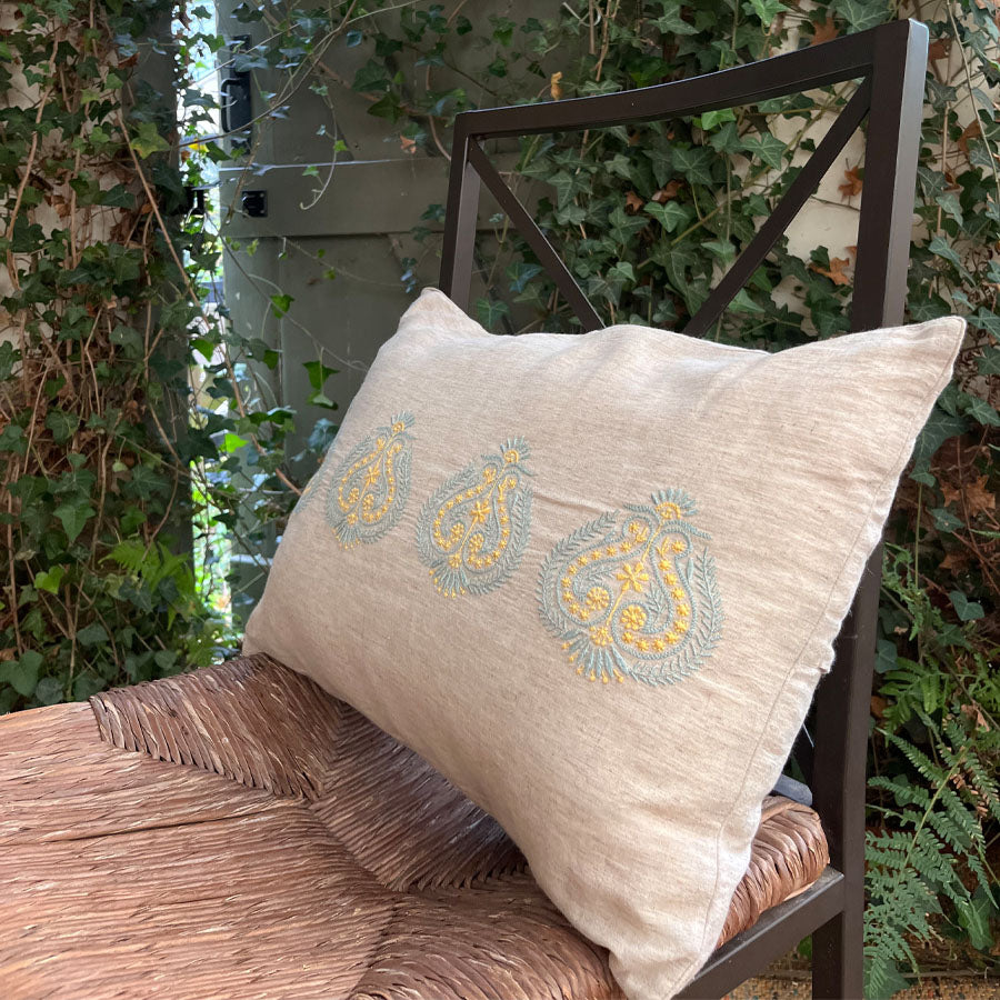 Kesar Chikankari cushion cover in soft beige on a chair outdoors