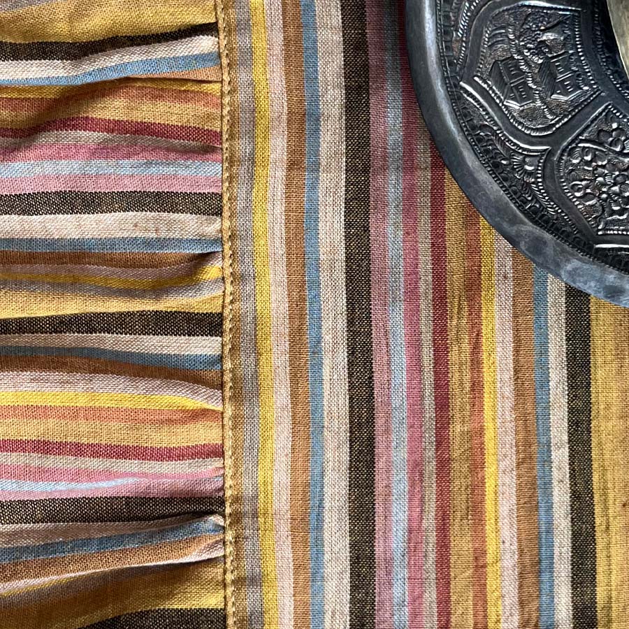 Close-up of mustard yellow stripped placemats with ruffled edges