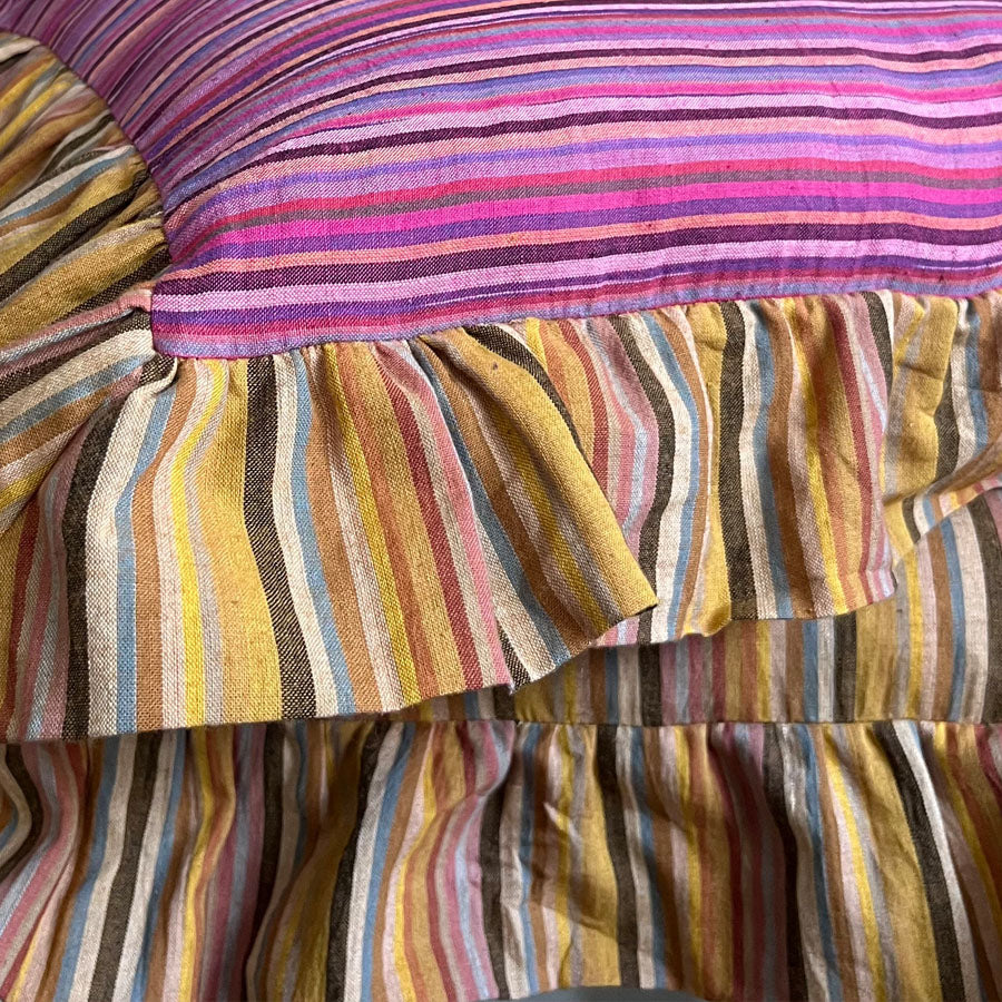Stach of pink striped pillow cover with yellow striped ruffles