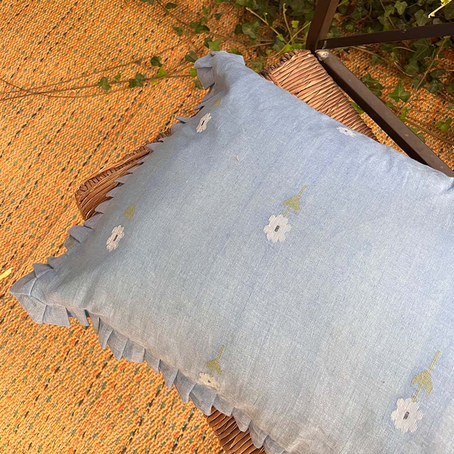 Sapphire blue Jamdani cushion cover with handwoven floral motifs and soft ruffle edges.