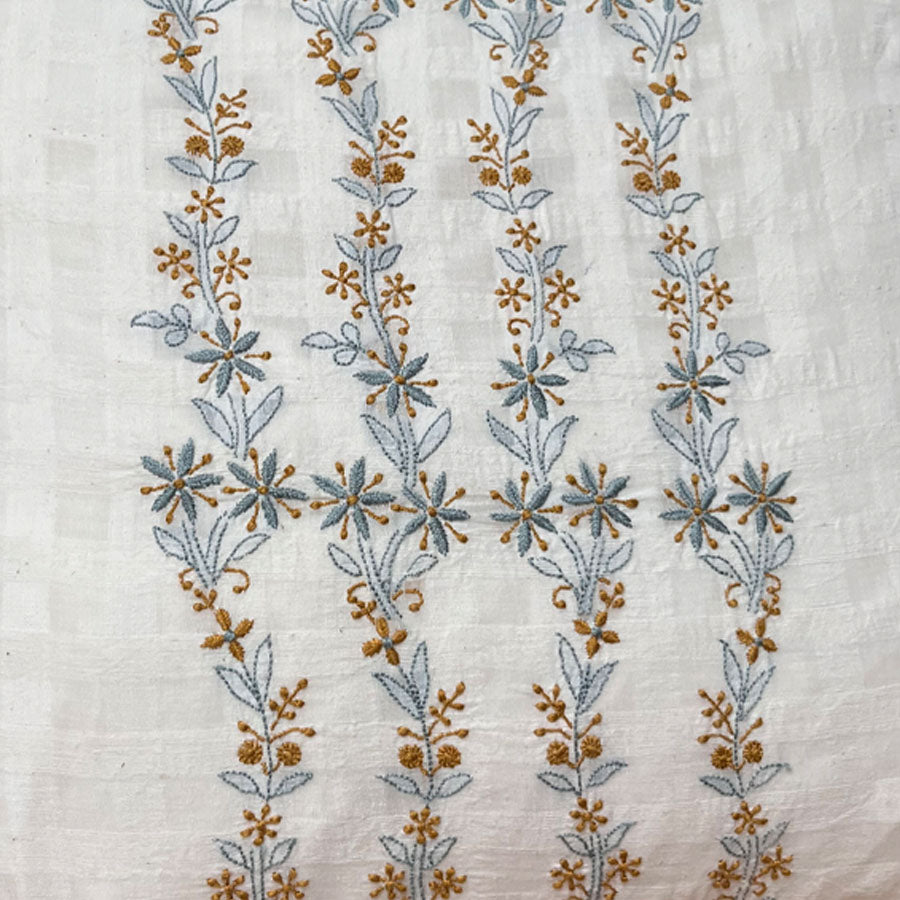Close-up of golden bluebell Chikankari cushion cover featuring a delicate trailing hand embroidery in golden yellow and light blue