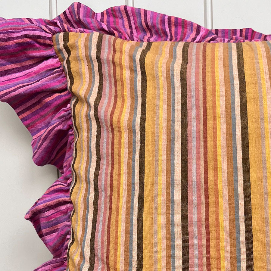 Close-up of yellow striped cushion cover with ruffled edge in pink against a white background
